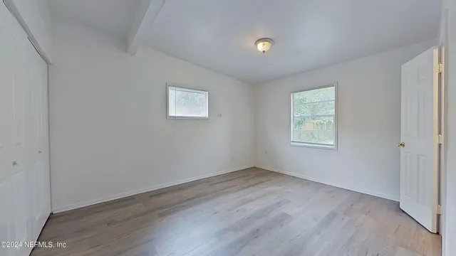 an empty room with wooden floor and windows