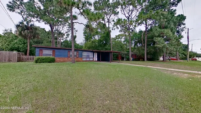 a front view of house with yard and trees in the background