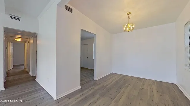 a view of an empty room with wooden floor and a mirror