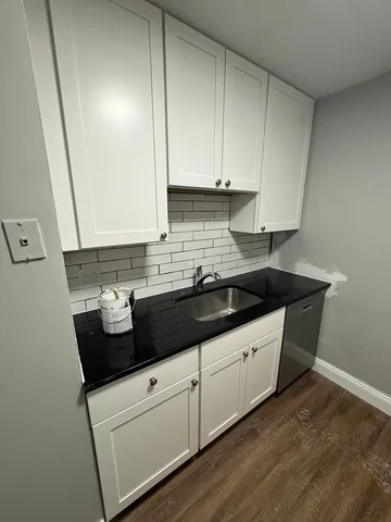 a kitchen with granite countertop white cabinets and a sink