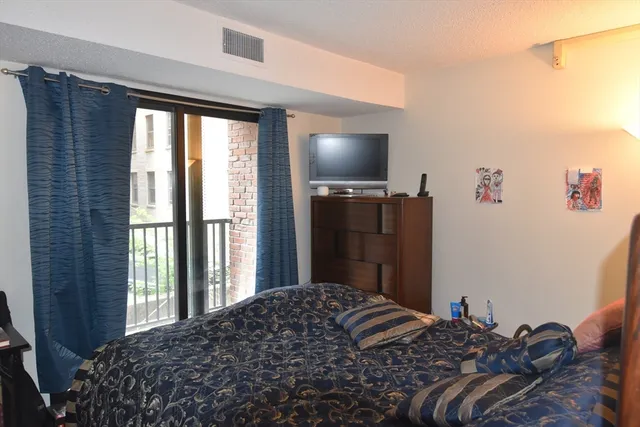 a bedroom with a bed flat screen tv and a large window