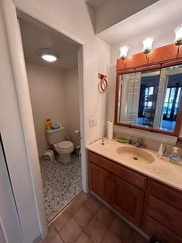a spacious bathroom with a granite countertop sink a toilet and a mirror