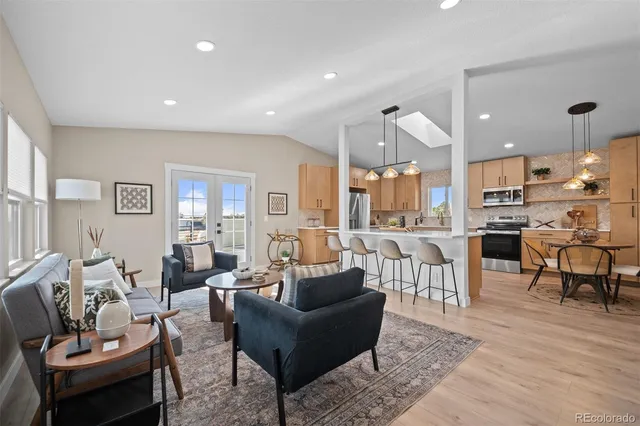 a living room with furniture kitchen view and a wooden floor