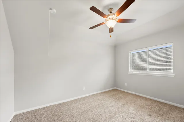 an empty room with a ceiling fan and window
