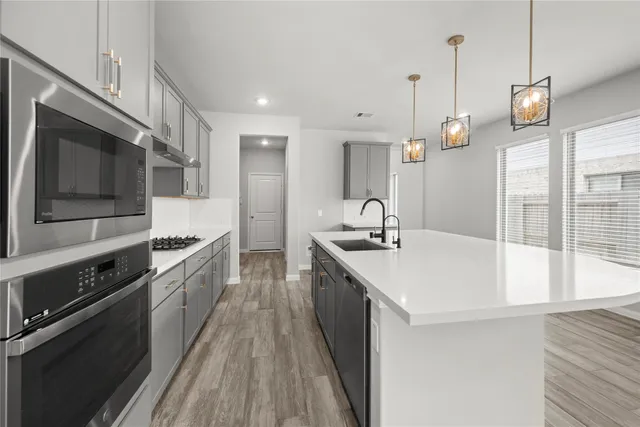 a kitchen with stainless steel appliances a sink a stove and a wooden floors