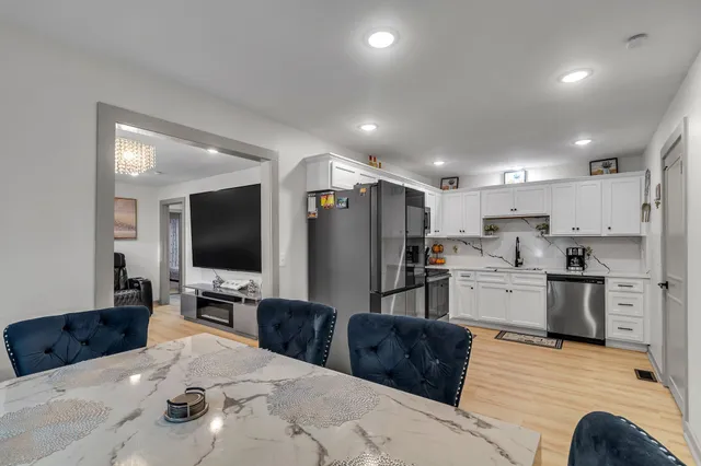 a large kitchen with stainless steel appliances kitchen island granite countertop a refrigerator and a stove top oven with wooden floor