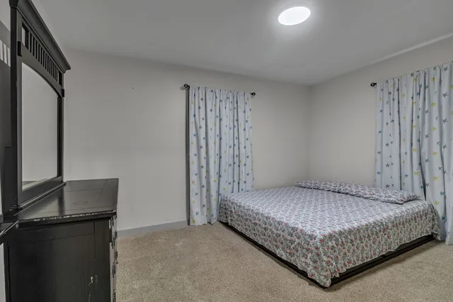 a bedroom with a bed and a flat tv screen on the dresser