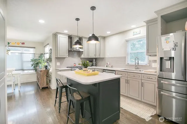 a kitchen with stainless steel appliances granite countertop a sink a stove a refrigerator and island with wooden floor