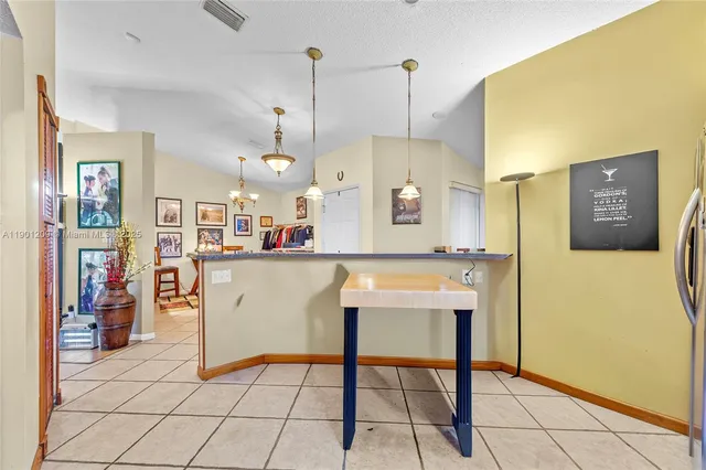a view of kitchen with stainless steel appliances kitchen island granite countertop dining table chairs and a rug