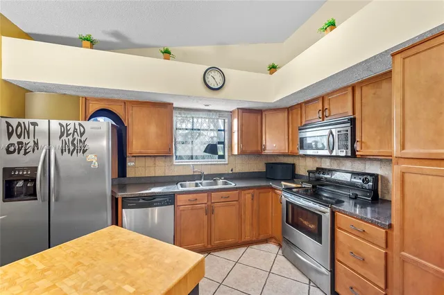 a kitchen with stainless steel appliances granite countertop a stove a sink and a refrigerator