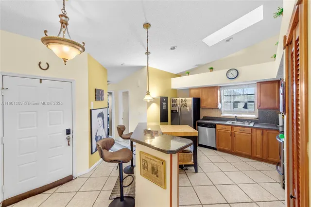 a kitchen with stainless steel appliances kitchen island granite countertop a table chairs and a refrigerator