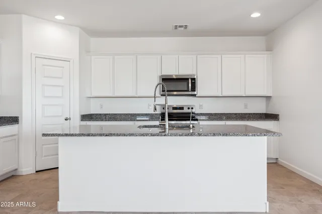 a kitchen with granite countertop a sink a stove a microwave and cabinets