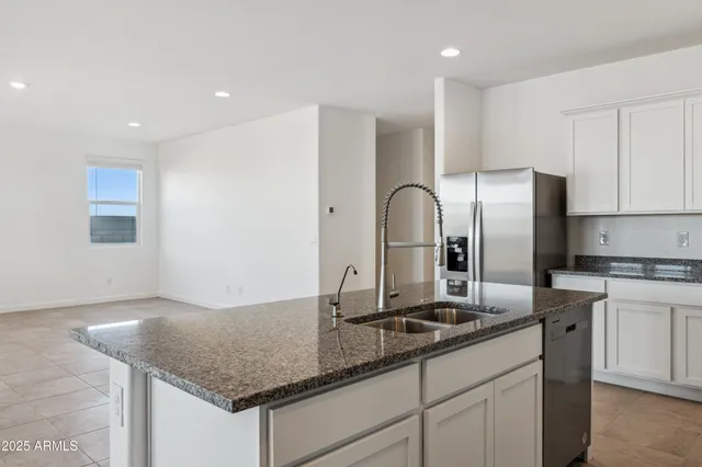 a kitchen with granite countertop a sink cabinets and stainless steel appliances