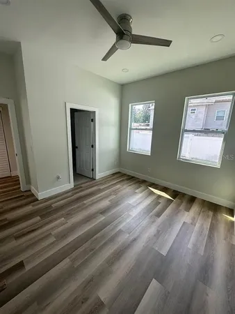 a view of an empty room with wooden floor and a window