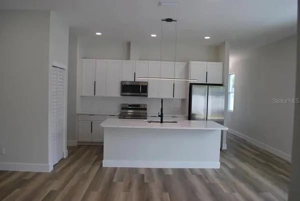 a large kitchen with stainless steel appliances a large counter top a stove and a refrigerator