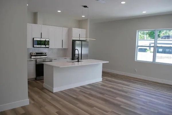 a kitchen with kitchen island white cabinets and stainless steel appliances