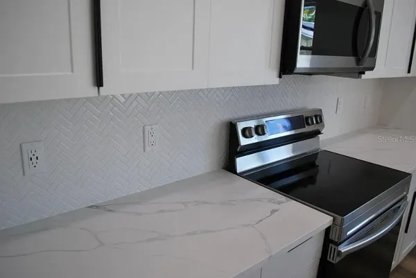 a kitchen with white cabinets and black appliances