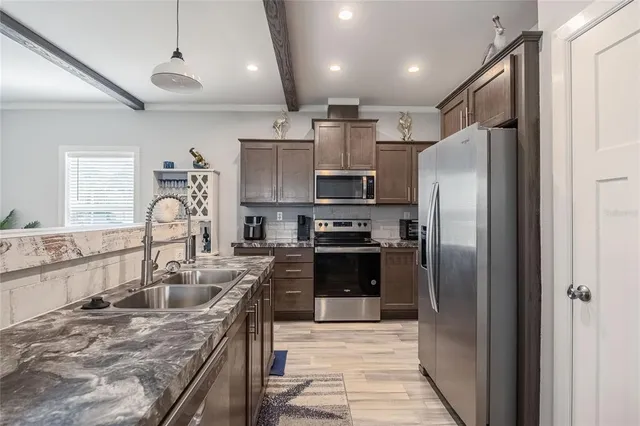 a kitchen with stainless steel appliances granite countertop a refrigerator a sink and a stove