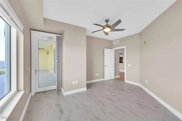 an empty room with window and ceiling fan