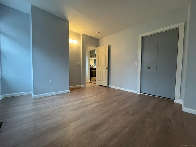 a view of an empty room with wooden floor and closet