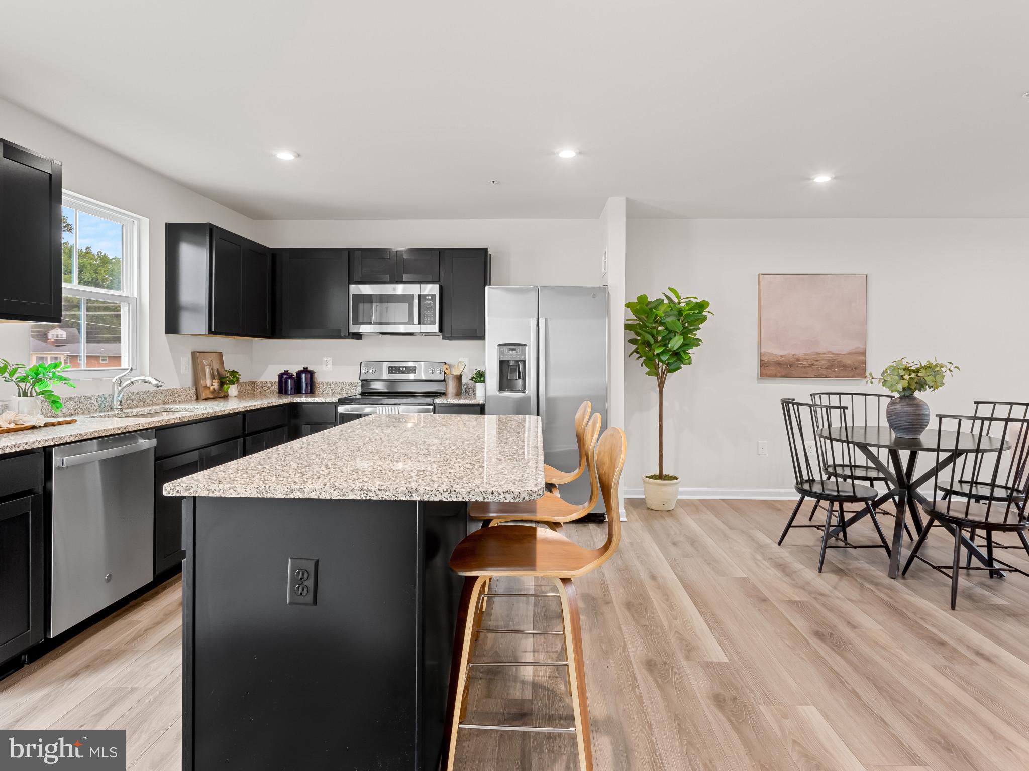 5505 Vergo Road Capitol Heights, MD 20743 - Photo 9 of 42 a kitchen with stainless steel appliances granite countertop a stove top oven a sink a dining table and chairs with wooden floor