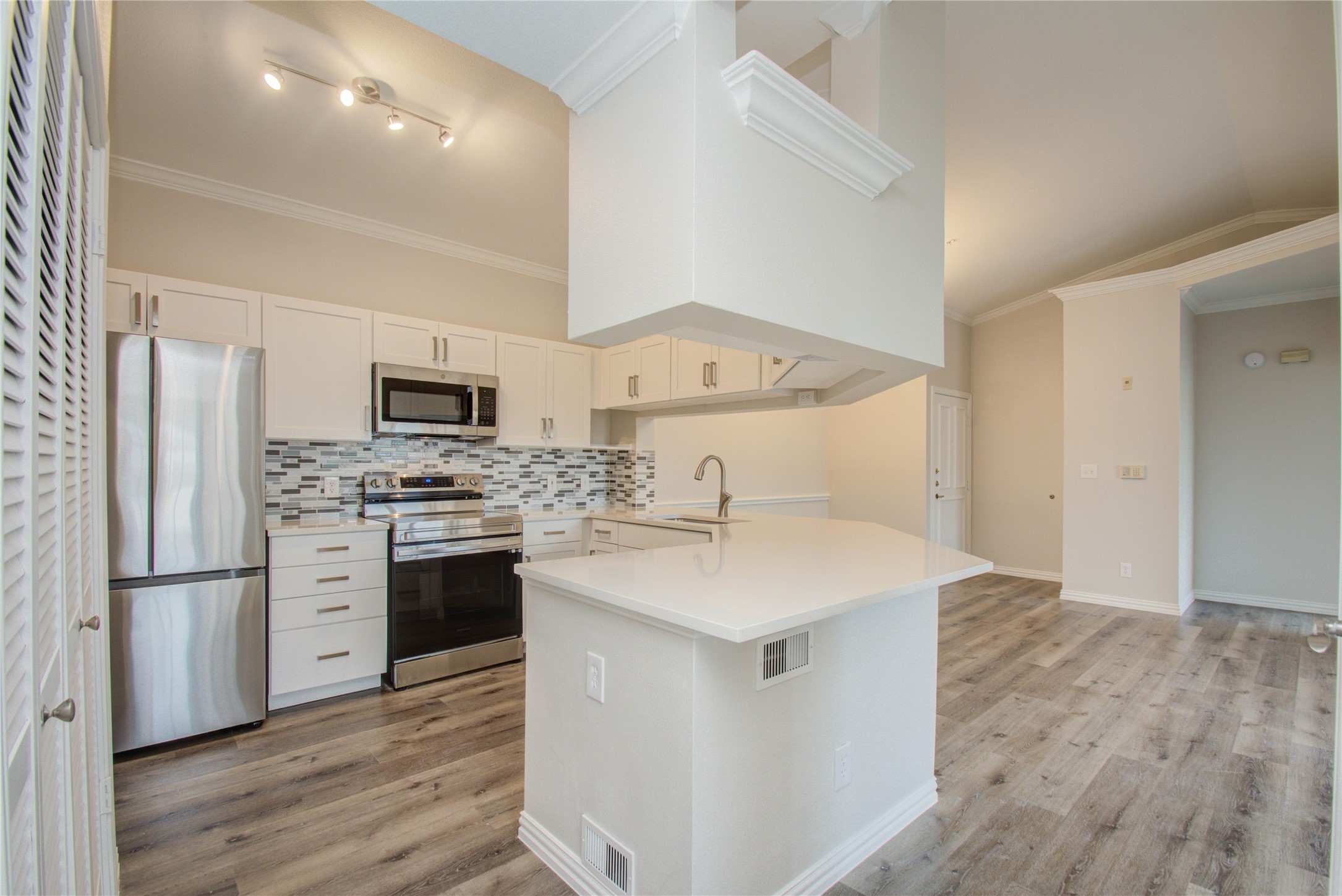 2111 Welch Street, Unit A321 Houston, TX 77019 - Photo 4 of 25 a kitchen with stainless steel appliances a sink dishwasher a refrigerator a stove and white cabinets with wooden floor