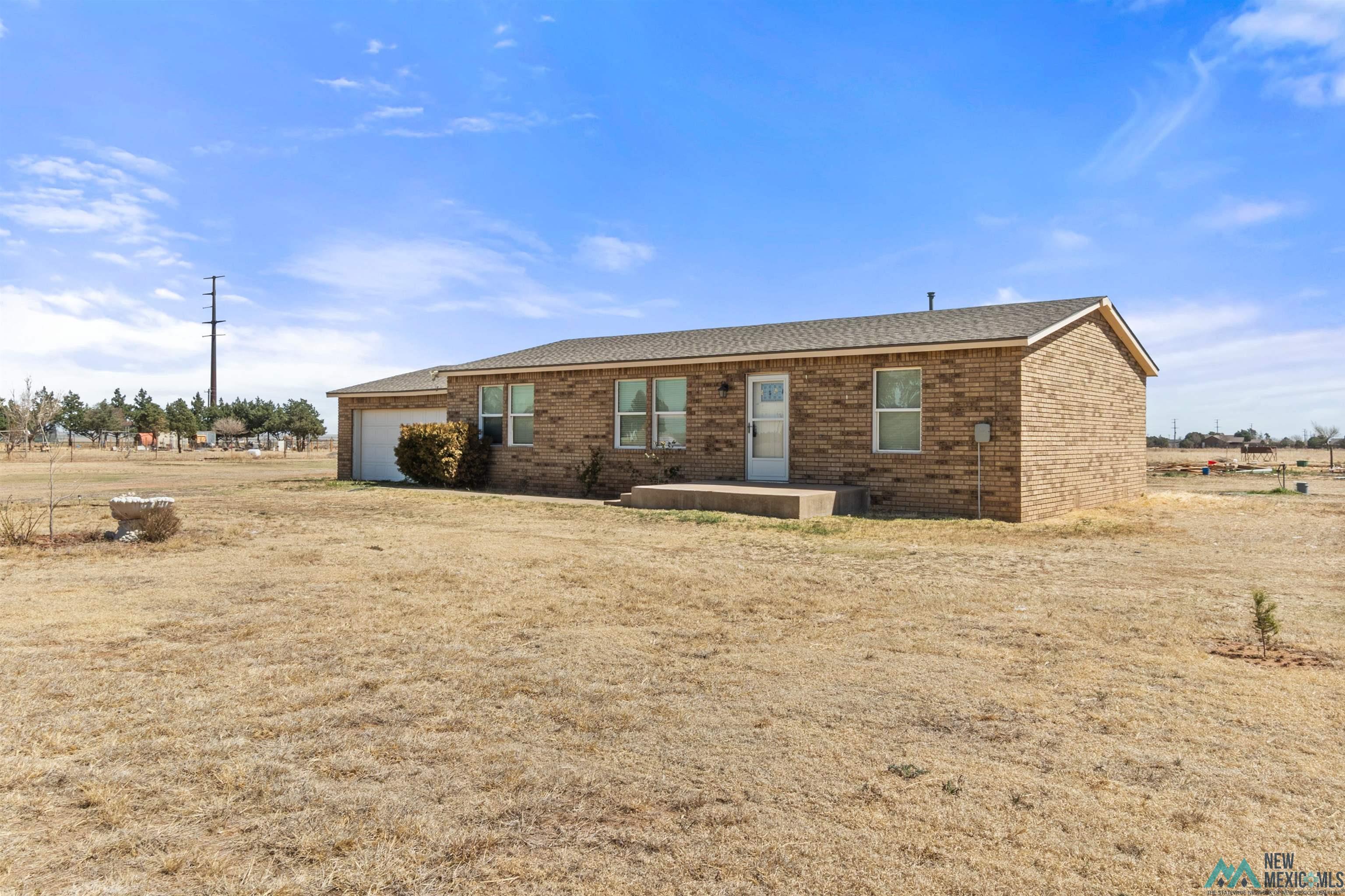 1691 County Rd K Clovis, NM 88101 - Photo 18 of 22 Rear view of property featuring brick siding, a garage, and roof with shingles