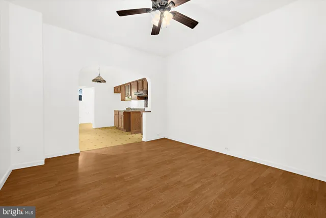 a view of empty room with wooden floor and ceiling fan