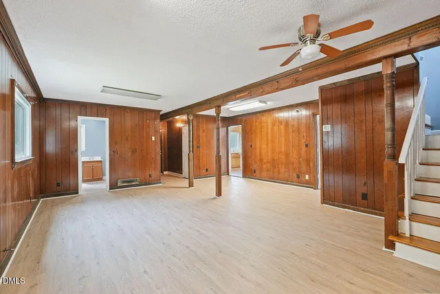 a view of an empty room with wooden floor and stairs