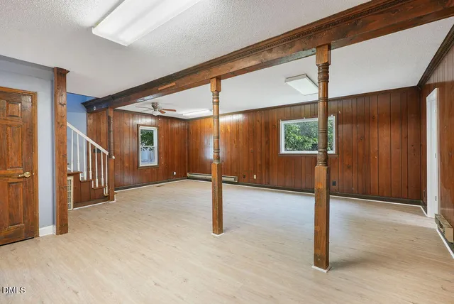 an empty room with wooden floor closet and windows