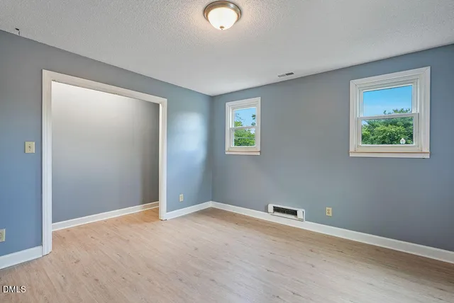 an empty room with windows and closet