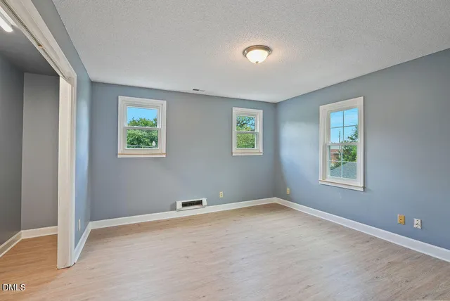 an empty room with wooden floor and windows