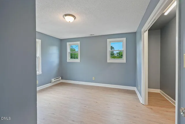 an empty room with wooden floor and windows