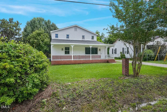 a view of a house with a yard and a large tree