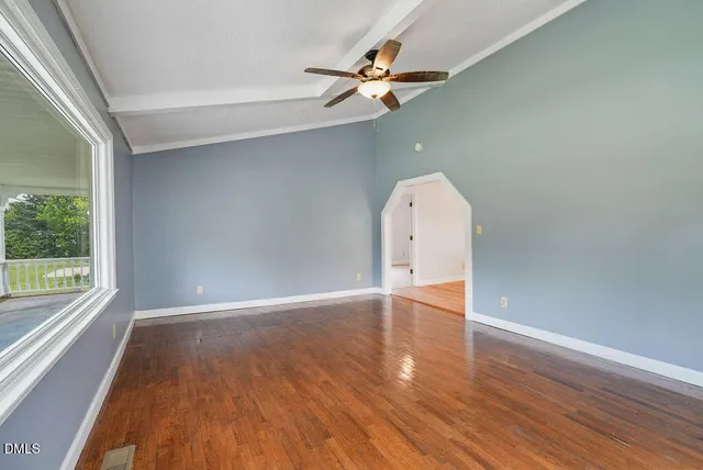 an empty room with wooden floor fan and windows