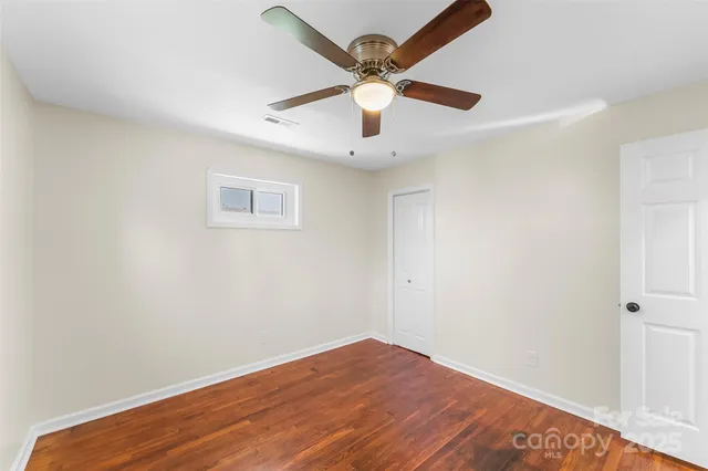 an empty room with wooden floor and ceiling fan
