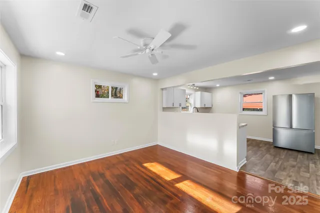 a view of kitchen and empty room with wooden floor