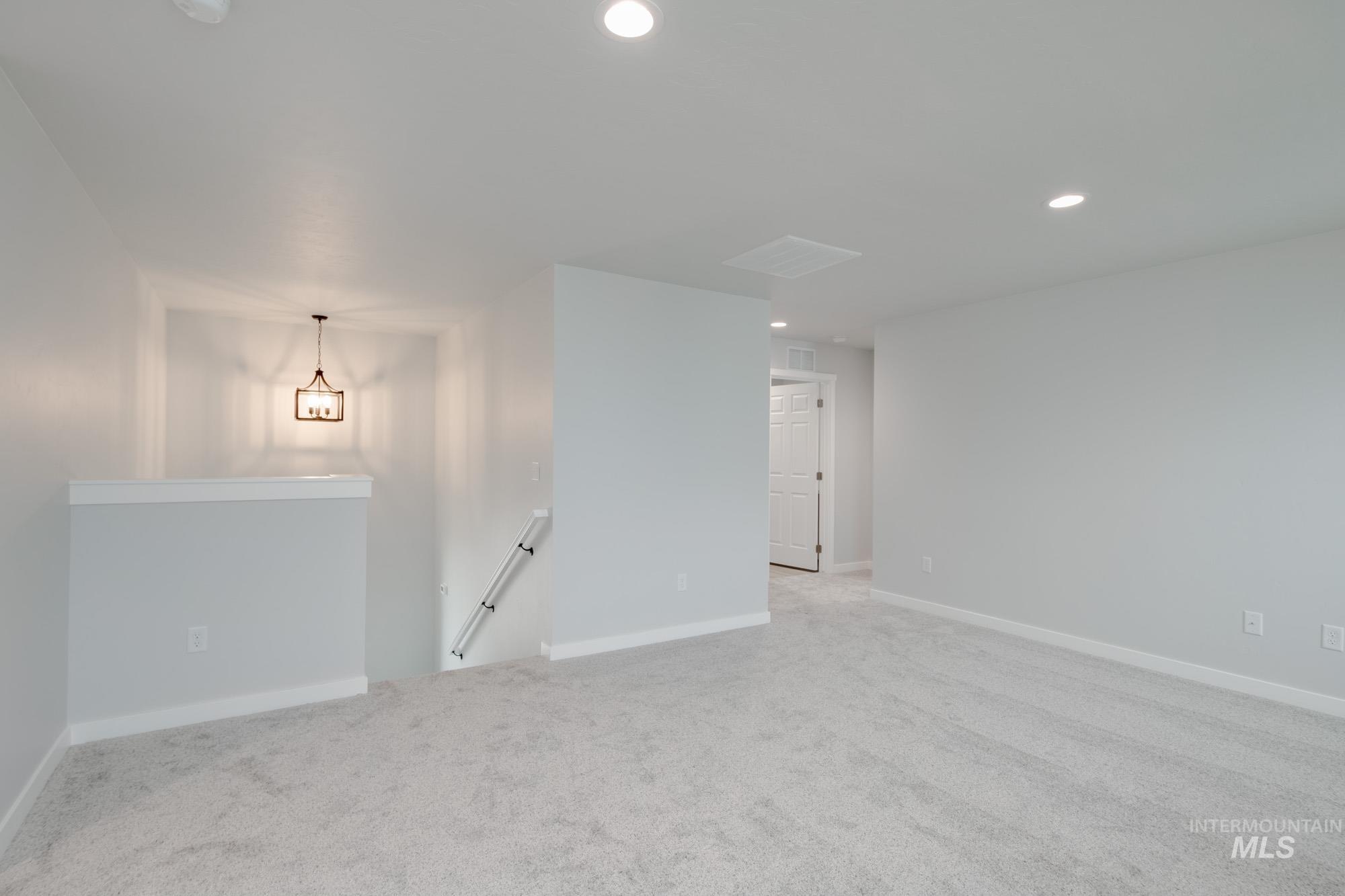 2391 West Fallon Loop Nampa, ID 83651 - Photo 16 of 20 Spacious carpeted room featuring recessed lighting, a contemporary chandelier, light gray walls, white trim, and a paneled door