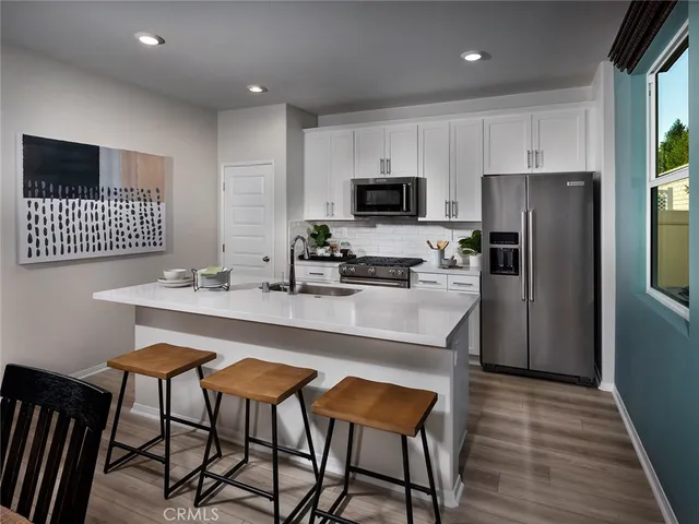 a kitchen with stainless steel appliances a kitchen island hardwood floor sink and stove