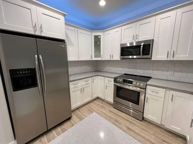 a kitchen with stainless steel appliances white cabinets a sink a stove a microwave and cabinetry