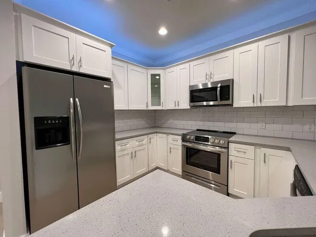 a kitchen with stainless steel appliances granite countertop a refrigerator a stove a sink and a microwave