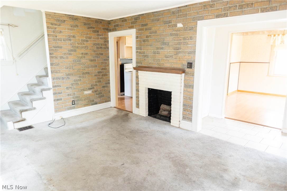 1371 Crescent Road Southwest Canton, OH 44710 - Photo 5 of 14 Unfurnished living room featuring brick wall, hardwood / wood-style floors, and a fireplace