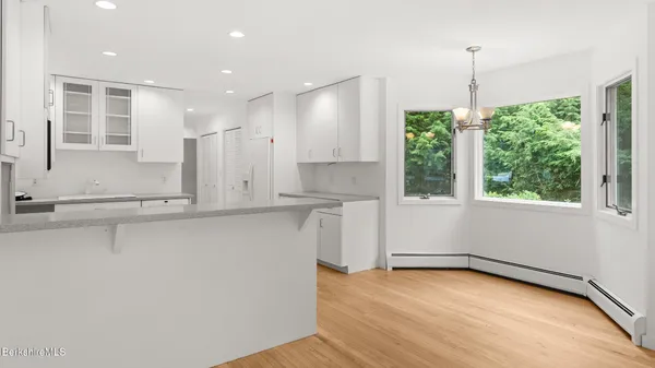 an empty room with wooden floor fireplace and windows