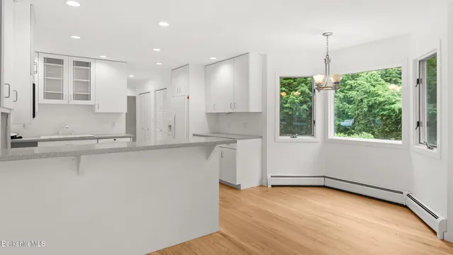 an empty room with wooden floor fireplace and windows