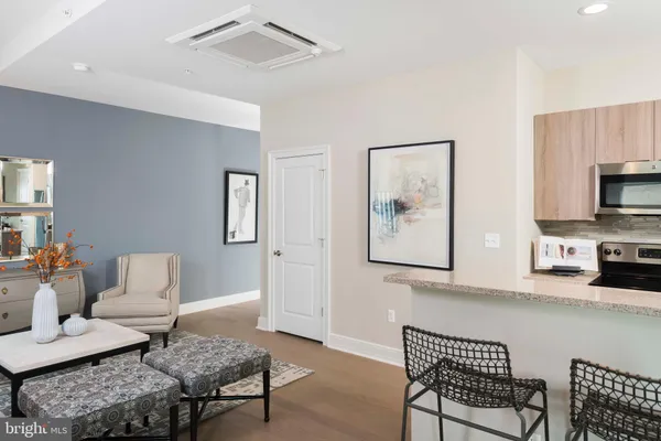 a kitchen with stainless steel appliances kitchen island granite countertop a stove a refrigerator a dining table and chairs with wooden floor