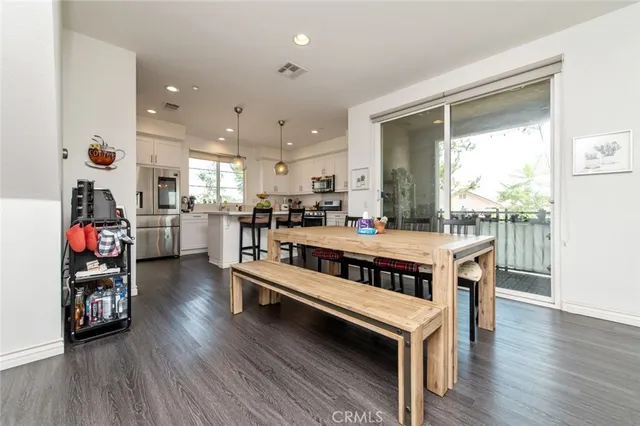 a kitchen with stainless steel appliances kitchen island granite countertop a refrigerator a stove a sink and a dining table with wooden floor