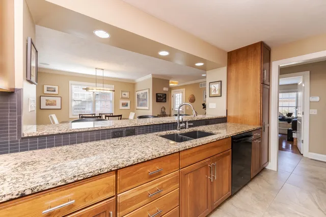 a kitchen with stainless steel appliances granite countertop a stove top oven a sink a counter space and living room view