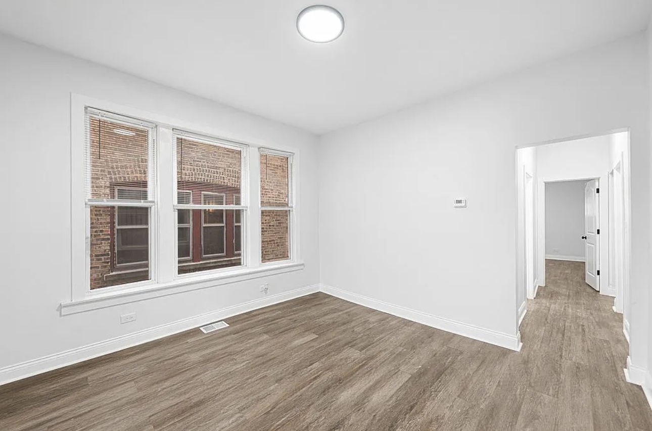 7912 South Ada Street, Unit 1 Chicago, IL 60620 - Photo 3 of 10 an empty room with wooden floor and windows