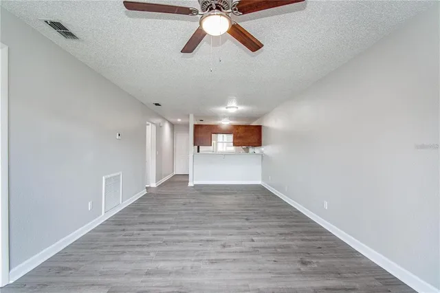 a view of empty room with wooden floor and ceiling fan