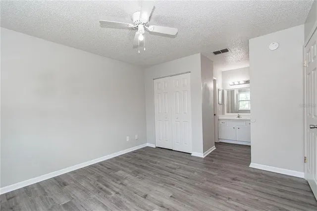 an empty room with wooden floor and a ceiling fan